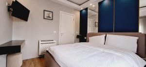 Un dormitorio con una gran cama blanca y una pared azul en gled apartment, en Tirana
