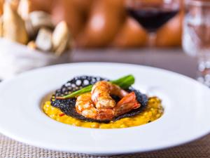 un plato blanco de comida con camarones y frijoles en Palladio Hotel Buenos Aires - MGallery en Buenos Aires