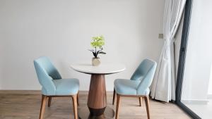 un tavolo con due sedie e un vaso con fiori di Căn hộ cao cấp tại ALaCarte Ha Long Bay Hotel Residence a Ha Long
