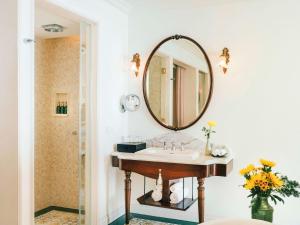 een badkamer met een wastafel en een spiegel bij Hôtel Perle d'Orient Cat Ba - MGallery in Cat Ba
