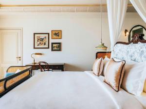 una camera da letto con un grande letto bianco con cuscini di Hôtel Perle d'Orient Cat Ba - MGallery a Cat Ba