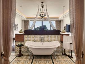 a bathroom with a tub and a large window at Hôtel Perle d'Orient Cat Ba - MGallery in Cat Ba