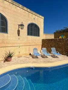 three chairs and a swimming pool in front of a building at Gozo Silence in Għarb