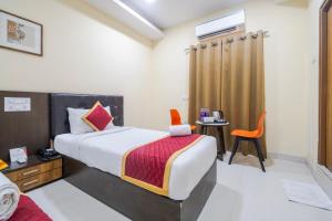 a bedroom with a bed and a table and a chair at Lemonridge Hotels Kukatpally in Hyderabad