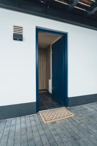 eine blaue Tür in einem weißen Gebäude mit Fliesenboden in der Unterkunft Hunsrück Valley View Apartment with Cedar SAUNA in Bruschied