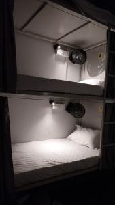 a bunk bed with white sheets and lights on it at NEW PG GOREGAON in Mumbai
