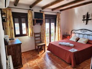 1 dormitorio con 1 cama con sábanas rojas y silla en Posada La Plaza, en Canillas de Albaida