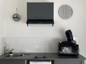 a kitchen with a sink and a clock on the wall at Chez Aurel in Raismes