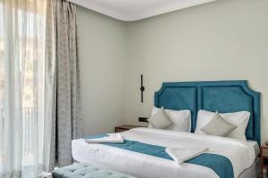 a bedroom with a bed with a blue headboard and a window at Hotel Baga Bliss By Celestiial Hospitality, Baga North Goa in Goa