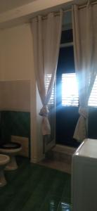 a bathroom with a toilet and a window with curtains at Casa Gaia in Palermo