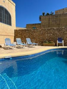 two chairs and a swimming pool in a building at Gozo Silence in Għarb