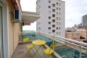 einen Balkon mit gelben Stühlen und einem Tisch auf einem Gebäude in der Unterkunft Cosy studio aperçu mer Monaco border in Beausoleil