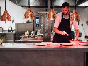 Een man in een keuken die borden klaarmaakt op een aanrecht. bij Mercure Avignon Gare TGV in Avignon