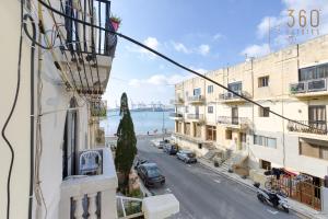 een balkon met uitzicht op een straat met gebouwen bij Charming 3BR Apt with Breathtaking Sea Views by 360 Estates in Birżebbuġa
