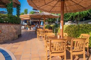a group of tables and chairs with umbrellas on a patio at Camping La Masia - Maeva Vacansoleil in Blanes