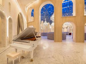 a white piano in a room with arches at Raffles Doha in Doha