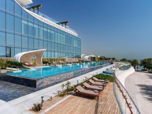 a hotel with a swimming pool and lounge chairs at Raffles Doha in Doha