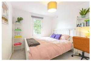 1 dormitorio con cama, escritorio y ventana en Stylish, 2 Bed Apartment, Muswell Hill en Londres