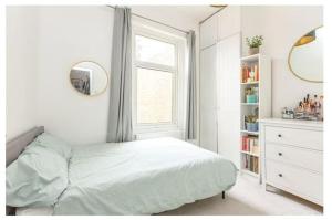 a white bedroom with a bed and a window at Stylish, 2 Bed Apartment, Muswell Hill in London
