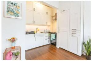 Il comprend une cuisine avec des placards blancs et du parquet. dans l'établissement Stylish, 2 Bed Apartment, Muswell Hill, à Londres