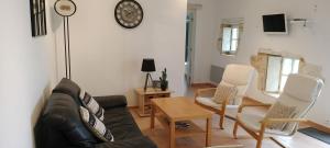 uma sala de estar com um sofá e cadeiras e um relógio em Gite La Grange aux Oiseaux em Conne-de-Labarde