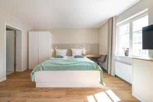 a white bedroom with a bed and a television at Design Apartments Potsdam - Luise in Potsdam