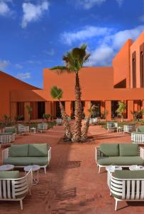 un bâtiment avec des chaises et un palmier en face de celui-ci dans l'établissement Doubletree By Hilton Ben Guerir Hotel & Residences, à Benguerir