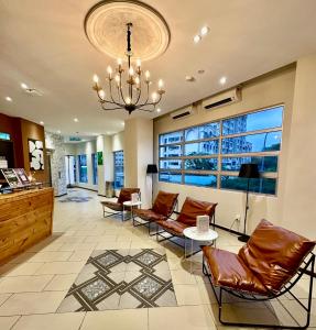 a lobby with leather chairs and a chandelier at Swing & Pillows - Apple Hotel Shah Alam in Shah Alam