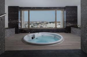 un bagno con ampia vasca e grande finestra di DoubleTree by Hilton Muscat Qurum a Mascate