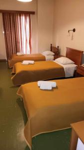 a hotel room with four beds with towels on them at Hotel Liberty in Missolonghi