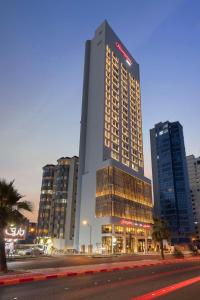 Hampton By Hilton Kuwait Salmiya في الكويت: مبنى طويل وبه أضواء عليه في مدينة