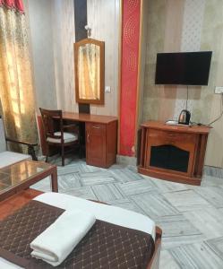 a room with a desk and a bed and a television at HOTEL RIZ VARANASI in Varanasi