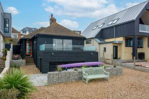 a black house with a bench in front of it at Pass the Keys Waders in Herne Bay