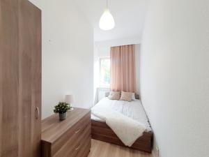 Habitación pequeña con cama y tocador de madera. en Tanie pokoje w centrum en Sopot