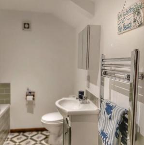 uma casa de banho branca com um lavatório e um WC em Heart of Kernow Holidays em Bugle