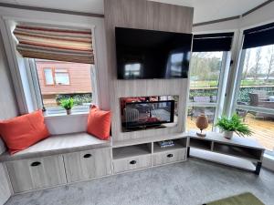 ein Wohnzimmer mit einem Flachbild-TV und einem Kamin in der Unterkunft Serenity Lodge, Tallington Lakes in Tallington