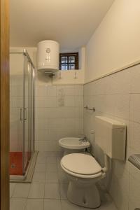 a white bathroom with a toilet and a sink at Albergo Diffuso Forgaria Monte Prat in Forgaria nel Friuli