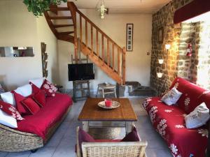 a living room with a red couch and a table at Domaine de l'Angevinière, 2 gîtes cosy, vue bocage proche Mont St-Michel in Saint-Laurent-de-Terregatte