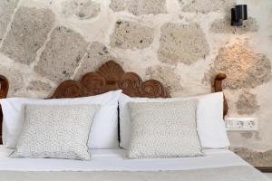 1 cama con almohadas blancas y pared de piedra en Apto Azahara - Casa San Marcial en Las Palmas de Gran Canaria