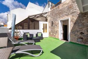 an outdoor patio with green flooring and chairs at Apto Azahara - Casa San Marcial in Triana