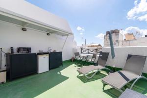 a balcony with chairs and a kitchen on a roof at Apto Azahara - Casa San Marcial in Triana