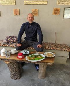 um homem sentado numa mesa com um prato de comida em Manokur e Basa Hotel em Minapin