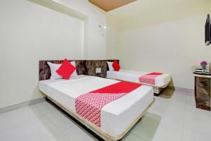 two beds in a white room with red pillows at Happy Homely Stay Near Pune Airport in Khadki