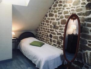 a bedroom with a bed with a mirror and a stone wall at Domaine de l'Angevinière, 2 gîtes cosy, vue bocage proche Mont St-Michel in Saint-Laurent-de-Terregatte