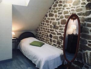 a bedroom with a bed with a mirror and a stone wall at Proche Mont St-Michel, deux maisons authentiques au cœur de la nature, domaine de l'Angevinière in Saint-Laurent-de-Terregatte