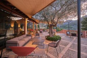 a patio with a couch and chairs and a tree at Hotel Valldemossa - New Opening 2024 in Valldemossa