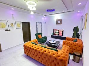a living room with an orange couch and two chairs at Luxe club des rois in Cotonou