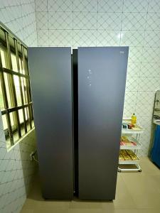 a stainless steel refrigerator in a kitchen next to a shelf at Luxe club des rois in Cotonou