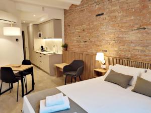 una camera con un letto bianco e un muro di mattoni di ARIQUS Fira Apartments a Hospitalet de Llobregat