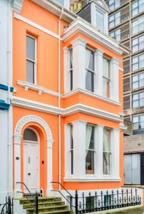 ein orangefarbenes und weißes Haus vor einer Stadt in der Unterkunft Plymouth Hoe - Beautiful 5 Bedroom Victorian House - Central Location in Plymouth